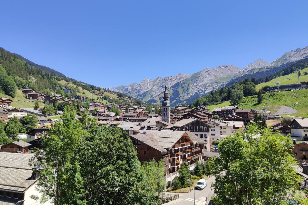 A mountain village with traditional wooden buildings, a church, and a clear view of the surrounding mountains.