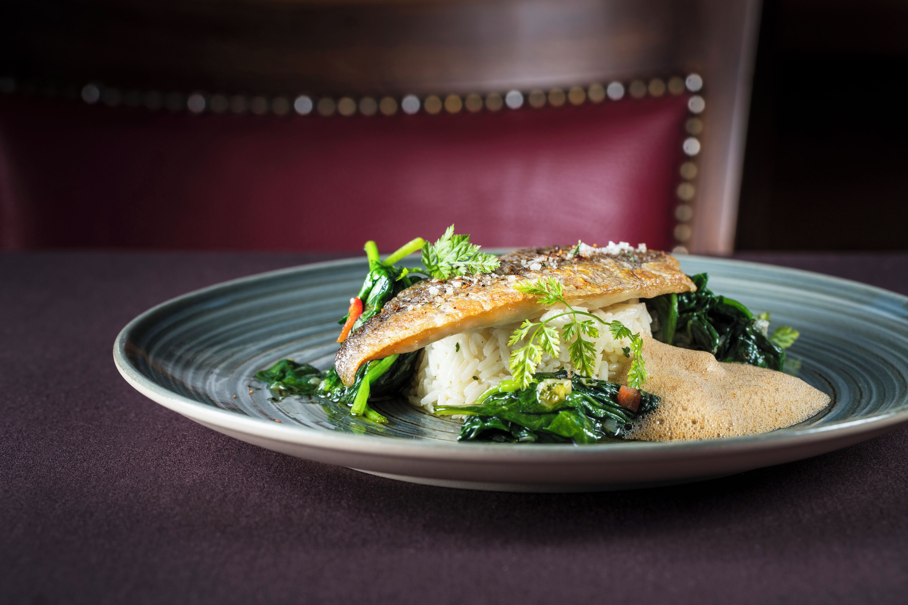 A plate of food with a fish, rice, and greens.