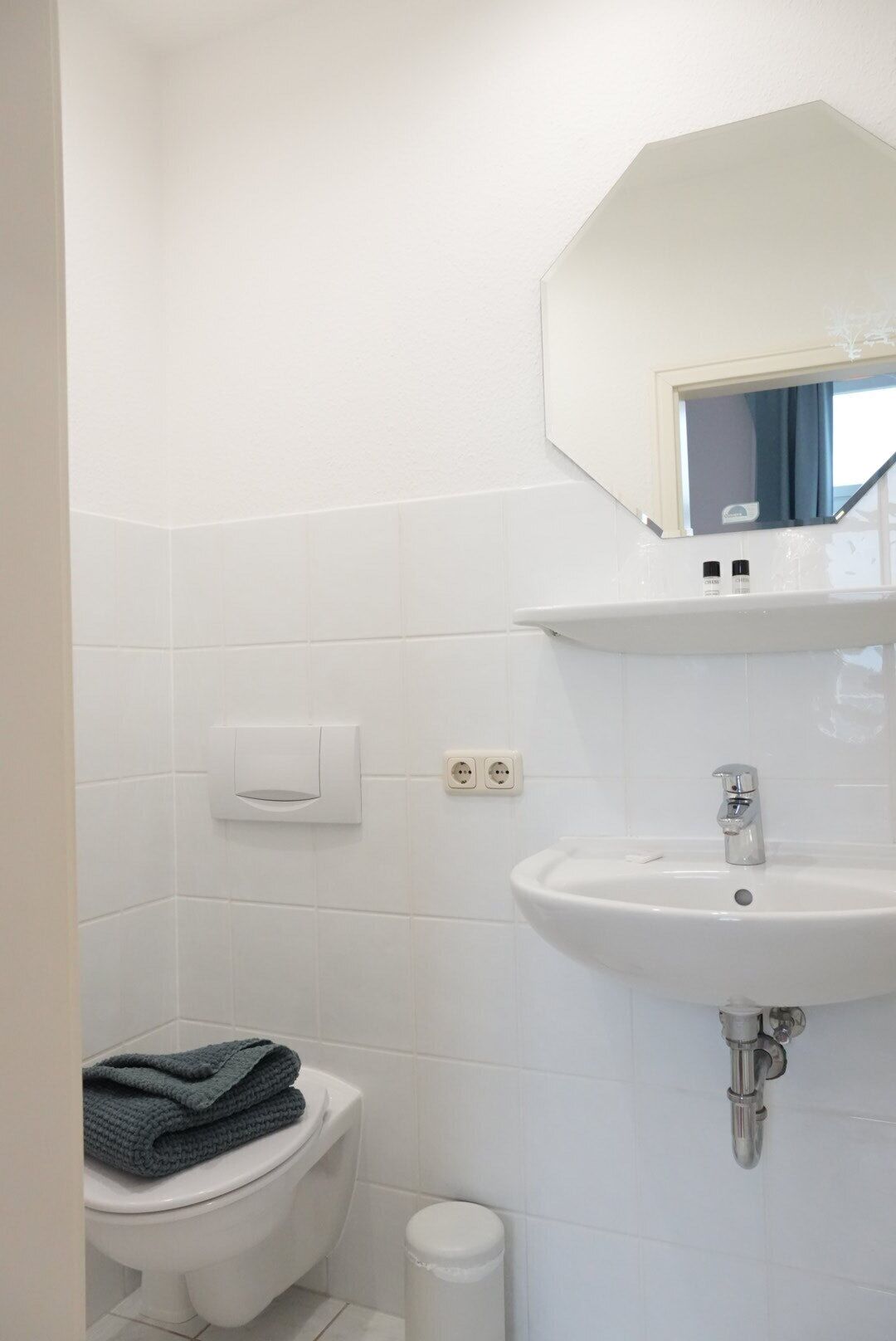 Et badeværelse med en hvid vask, et spejl og et toilet.