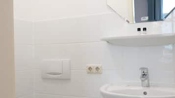 Et badeværelse med en hvid vask, et spejl og et toilet.