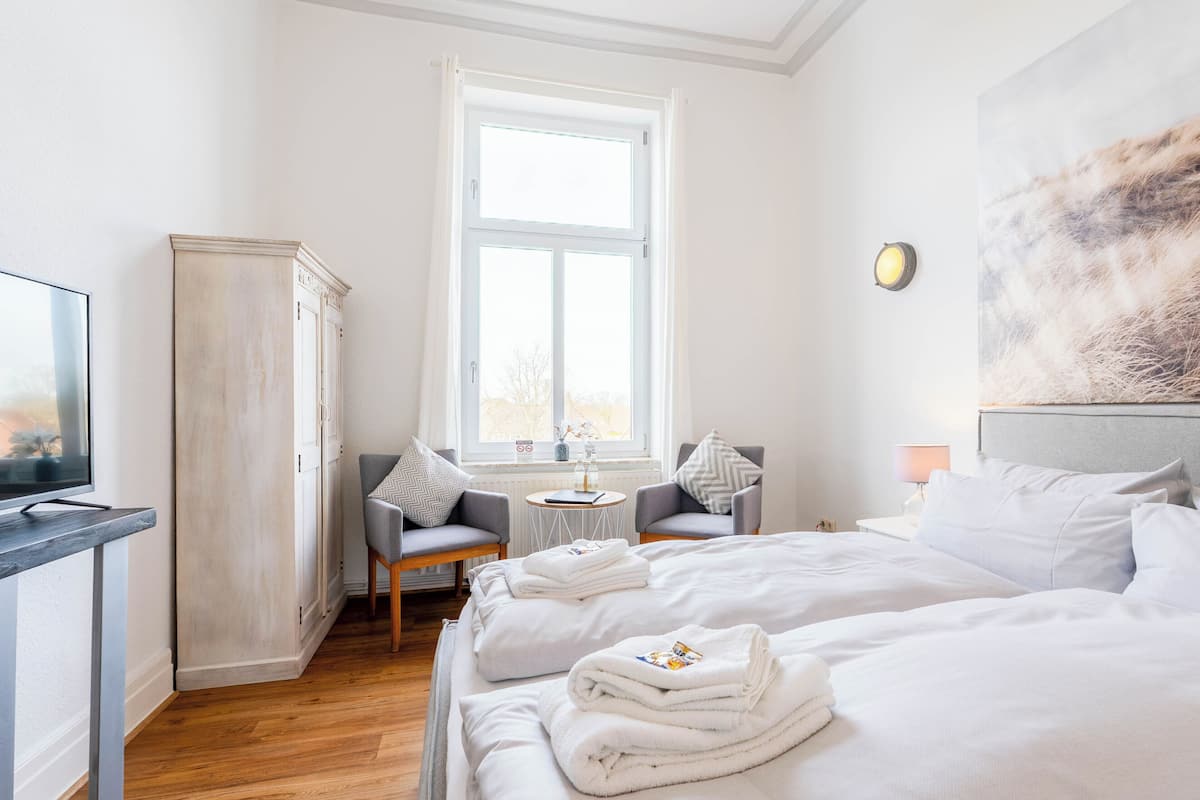 A hotel room with a bed, a desk, a chair, a wardrobe, and a window.