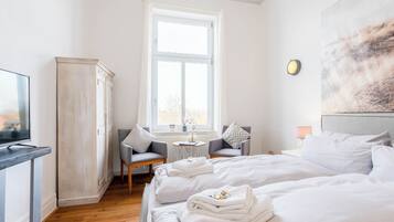 A hotel room with a bed, a desk, a chair, a wardrobe, and a window.