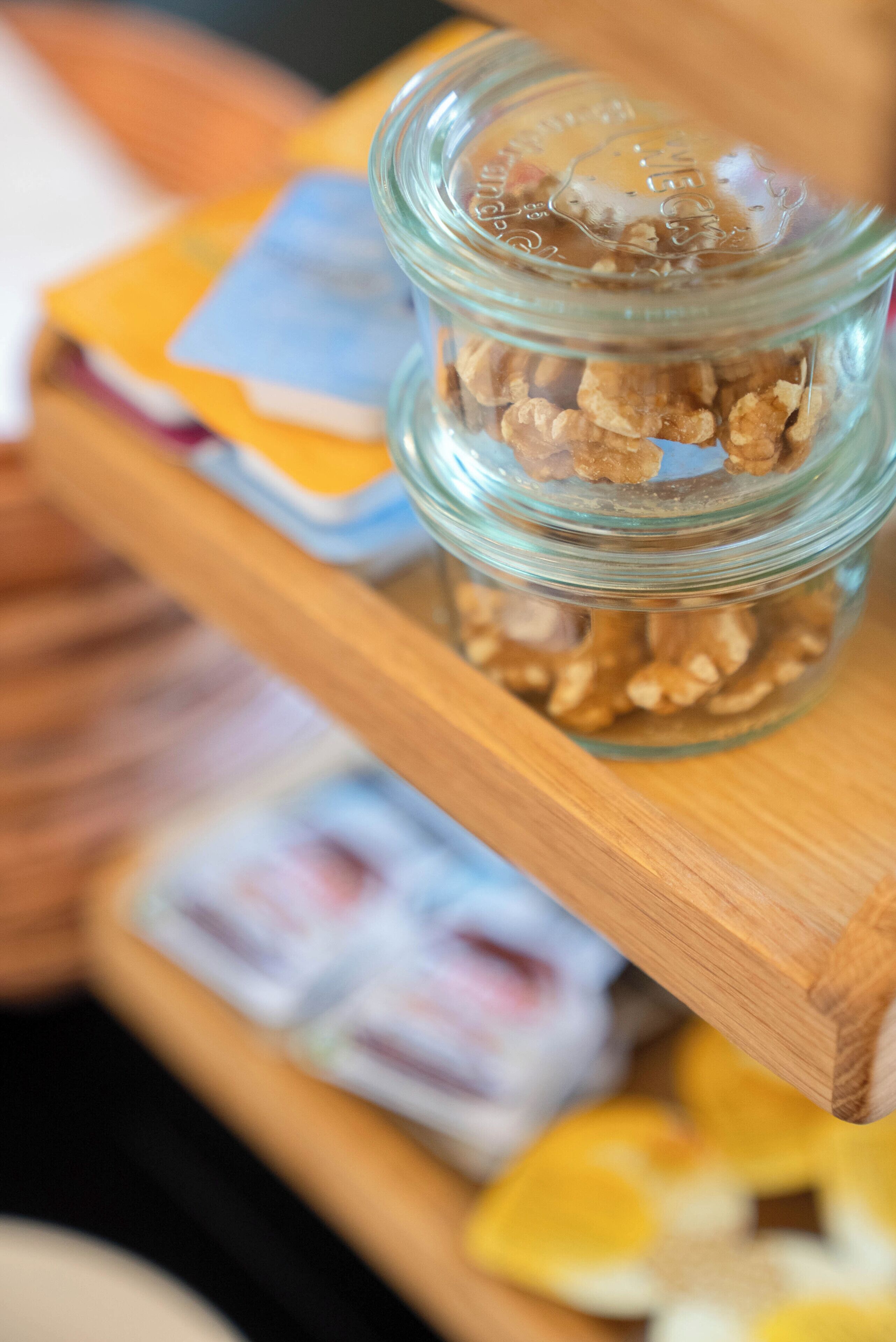 A glass jar with granola on a wooden shelf.