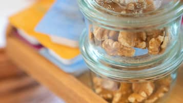 Um frasco de vidro com granola sobre uma prateleira de madeira.
