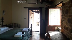 A bedroom with a bed, a chair, a table, a hanging light fixture, and a window. - Azienda Agrituristica Colle San Giorgio (Castiglione Messer Raimondo)