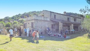 A stone building with a rustic exterior, surrounded by a grassy area with people. - Azienda Agrituristica Colle San Giorgio (Castiglione Messer Raimondo)