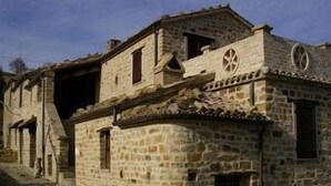 A stone building with a traditional design, featuring a central circular window and a small balcony. - Azienda Agrituristica Colle San Giorgio (Castiglione Messer Raimondo)