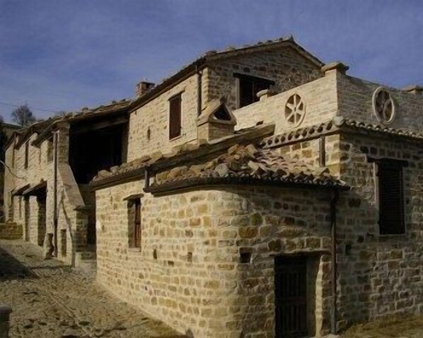 Un edificio de piedra con diseño tradicional, que presenta un ventanal circular central y un pequeño balcón.