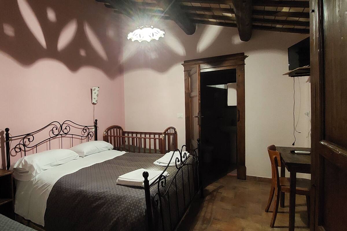 A bedroom with a bed, bedside table, and a desk with a chair.