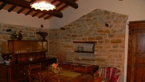 A cozy dining area with a stone wall, wooden furniture, and a chandelier. - Azienda Agrituristica Colle San Giorgio (Castiglione Messer Raimondo)