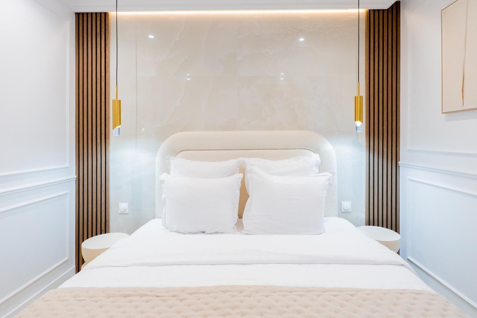 Ein modernes Hotelzimmer mit einem großen Bett, zwei Nachttischen und einer Wandleuchte.