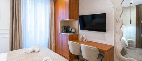 A hotel room with a bed, a desk with two chairs, a television, and a mirror.
