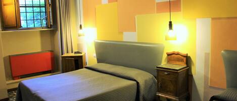 A hotel room with a bed, bedside tables, a window with curtains, and a red cabinet.