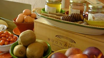 Una scatola di legno con l'etichetta “BUONAMICO”, sormontata da diversi frutti e barattoli.