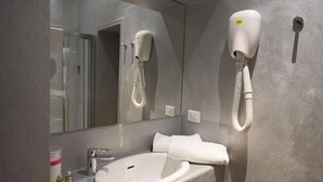 A bathroom with a white sink, a mirror, a hairdryer, and a towel rack. - Hotel Diana (Lucca)