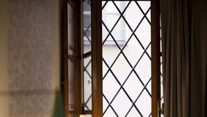 A room with a bed, a window with a metal grid, and a hanging light fixture. - Hotel Diana (Lucca)