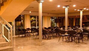 A conference room with rows of chairs and a staircase leading to an upper level.