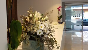 Un passadís amb un arranjament floral, una planta en test i una porta de vidre que dona a l'exterior.