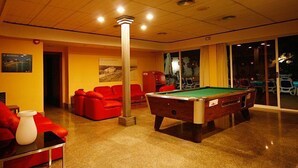 A billiards room with a pool table, red sofas, and a large pillar. - Hotel Perla (Benidorm)