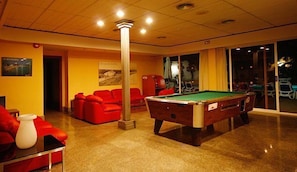 A billiards room with a pool table, red sofas, and a large pillar. - Hotel Perla (Benidorm)