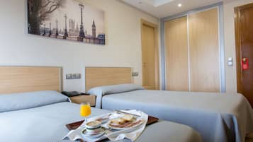A hotel room with two beds, a breakfast tray, and a painting of a cityscape.