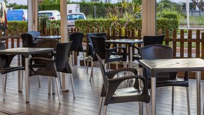 An outdoor patio with tables and chairs, surrounded by a wooden fence and greenery. - Hotel Olympia Ronda I (Puig)