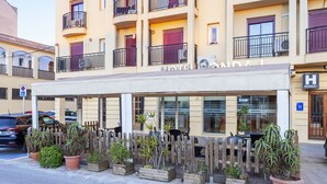 A hotel with a balcony, potted plants, and a sign indicating a handicap accessible entrance. - Hotel Olympia Ronda I (Puig)