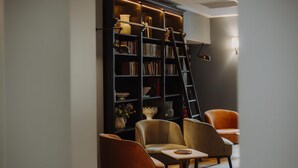 Una biblioteca moderna con estanterías, una escalera y dos sillones de cuero.