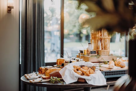 A breakfast buffet with various breads and pastries, a coffee station, and a view of the outdoors through a large window.. Les Demeures de Varennes, BW Signature Collection