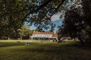 A large building with a symmetrical facade, a lawn with seating, and a clear sky. - Les Demeures de Varennes, BW Signature Collection (Varennes-Jarcy)