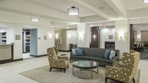 A lobby with a sofa, two armchairs, a coffee table, and a reception desk. - Homewood Suites by Hilton Cedar Rapids-North (Cedar Rapids)