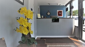 Un área de recepción con pared azul, un reloj y una planta.