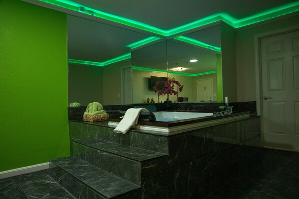 Un baño moderno con un espejo grande, una bañera y una pared de acento verde.
