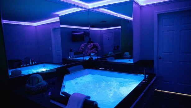 Un cuarto de spa con una bañera grande, un espejo y una puerta.