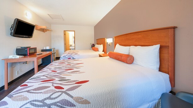 Habitación de hotel con dos camas, televisión, microondas y escritorio.