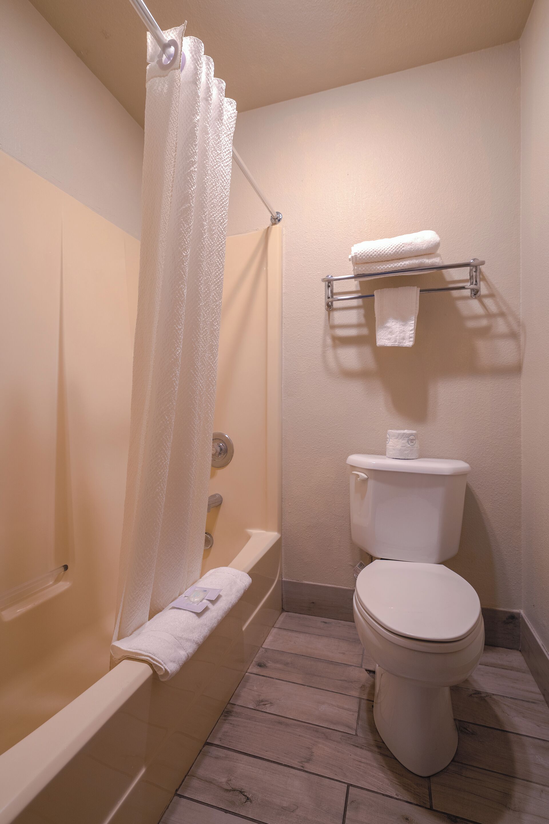 A bathroom with a bathtub, toilet, and a towel rack.
