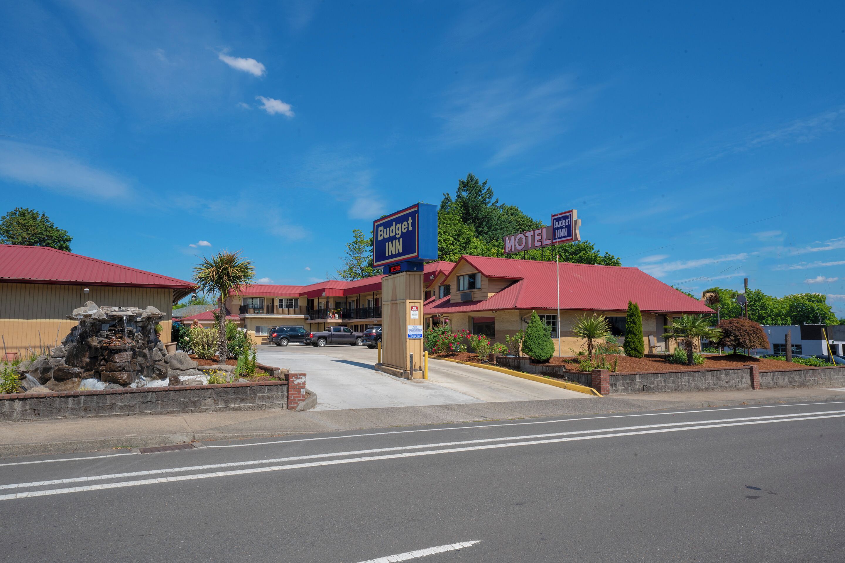 A motel with a red roof and a sign that reads "Budget Inn."
