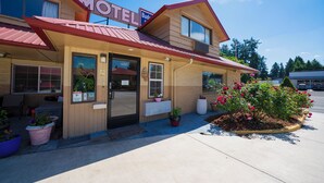 Un motel con techo rojo, un letrero y plantas en macetas afuera.