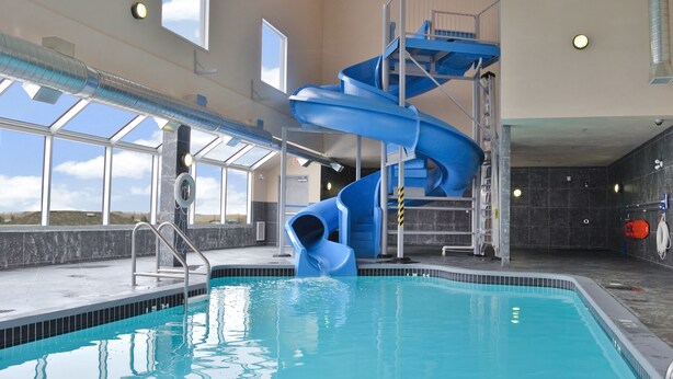 Una piscina interior con un tobogán azul y un puesto de socorristas.