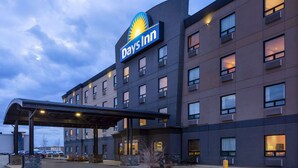 Un hotel Days Inn con diseño moderno, que cuenta con un cartel grande, varias ventanas y un área de estacionamiento techada.