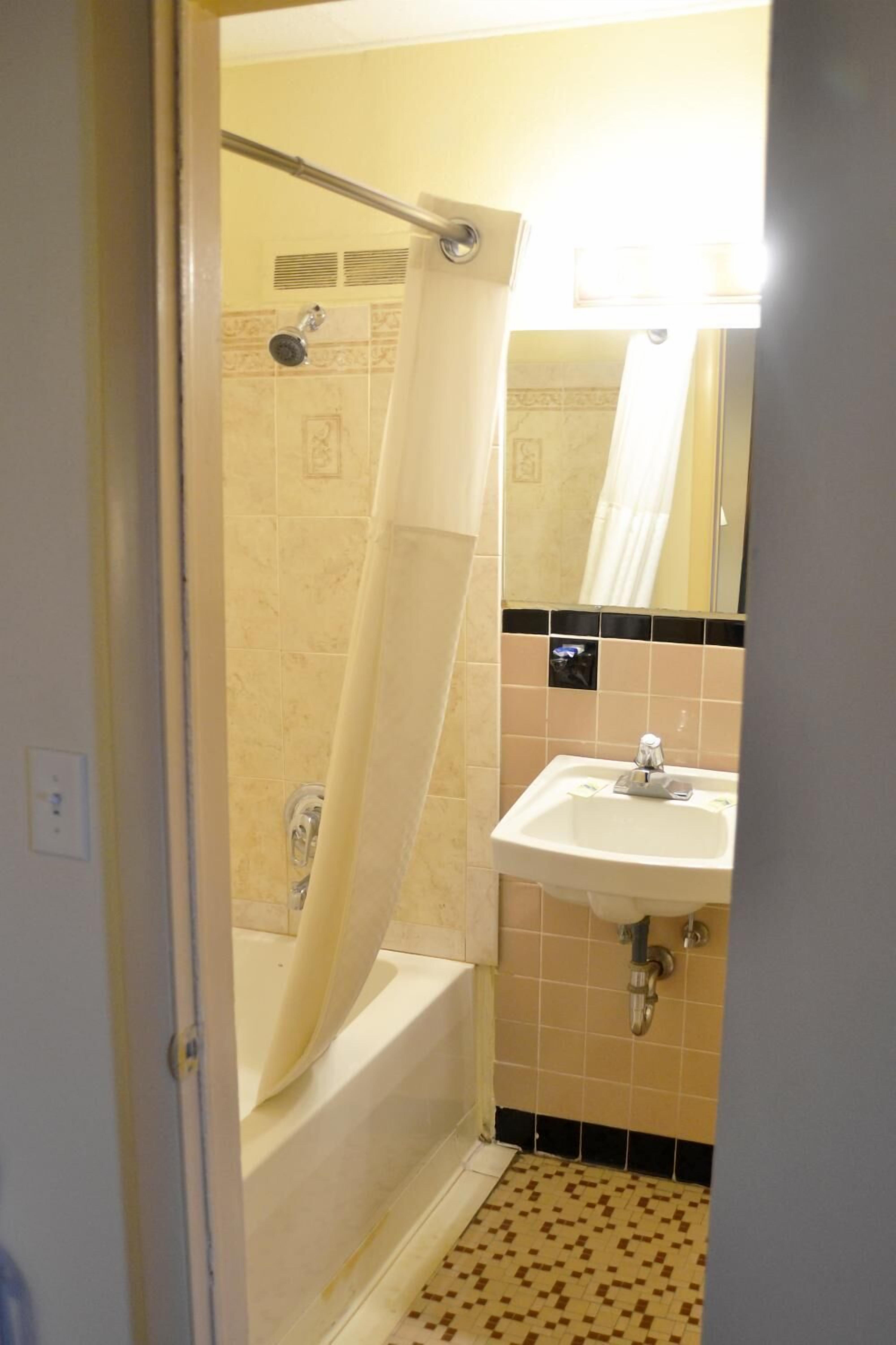Een badkamer met een bad, wastafel en douchegordijn.
