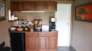 Una cucina compatta con mobili in legno, una macchina da caffè e un tostapane.