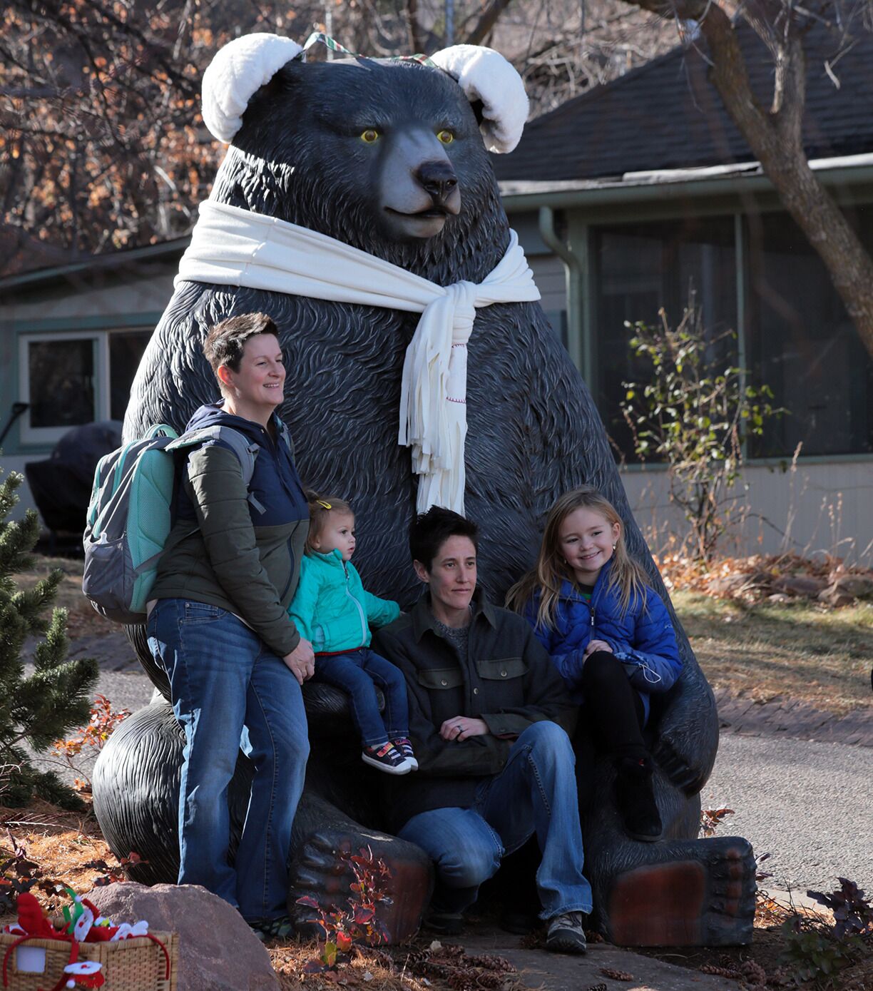 Una familia posa junto a una estatua grande de un oso, al aire libre.