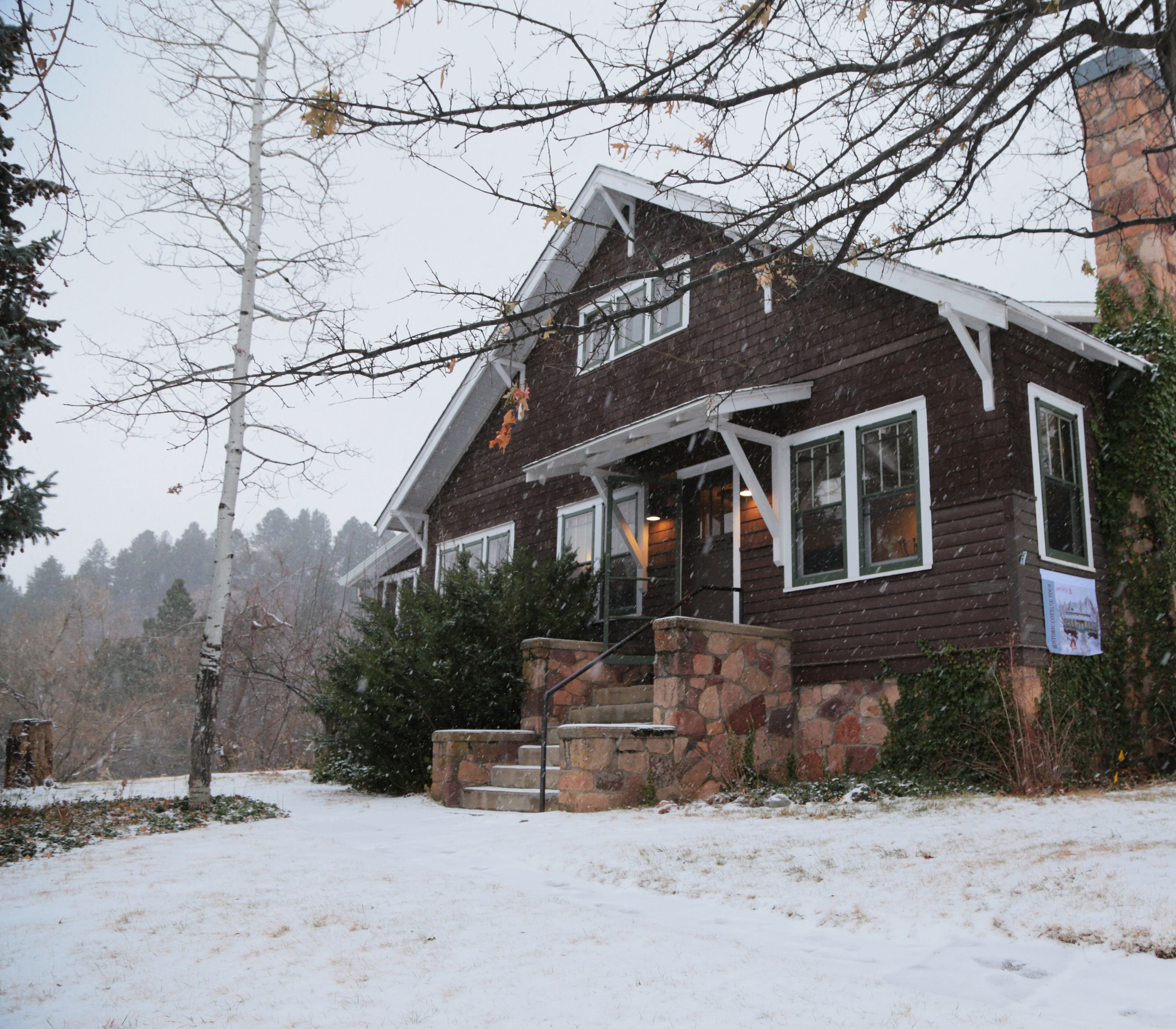 A two-story house with a stone foundation and a wooden exterior.