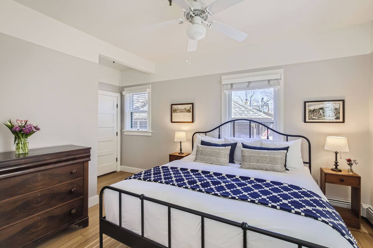 A bedroom with a bed, nightstands, a dresser, and a ceiling fan.