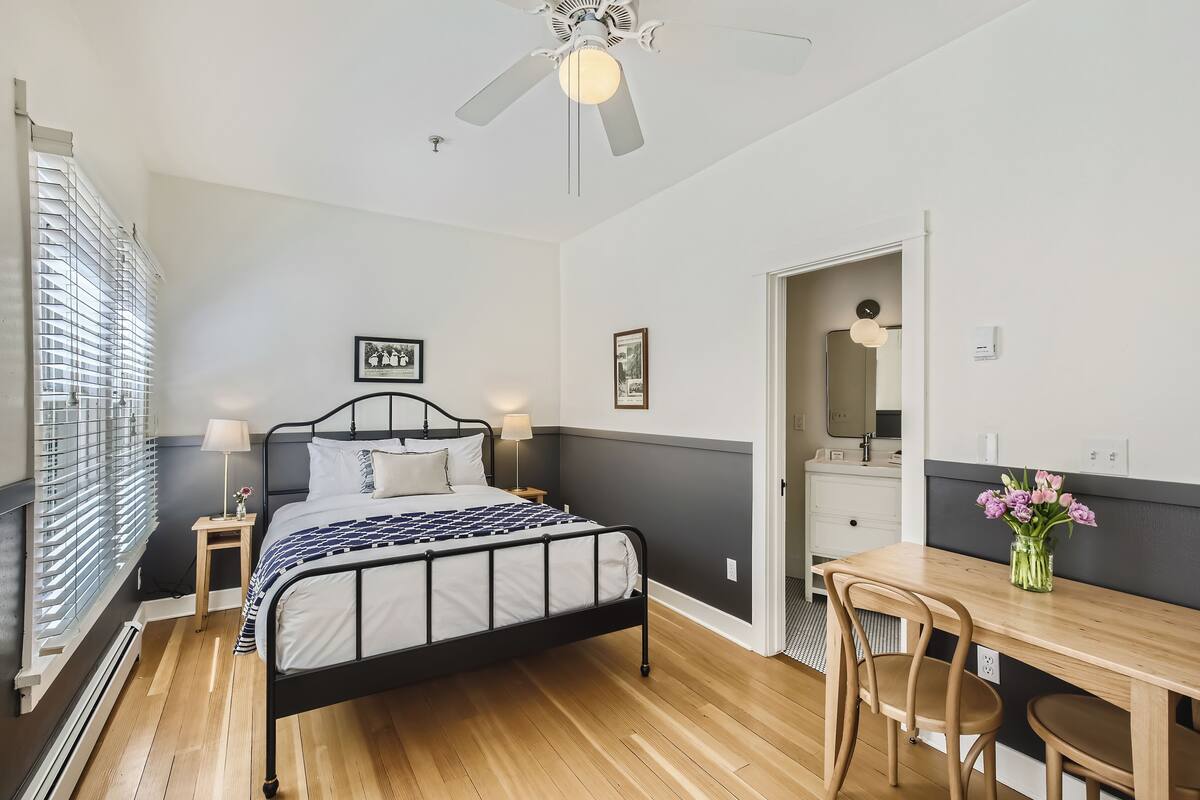 A bedroom with a bed, bedside tables, a desk, and chairs.