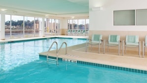 An indoor swimming pool with clear blue water, a no diving sign, and a seating area with chairs and towels. - SpringHill Suites by Marriott Macon (Macon)