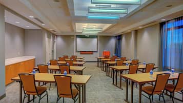 A conference room with tables and chairs, a podium, and a screen.