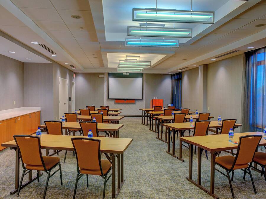 A conference room with tables and chairs, a podium, and a screen.