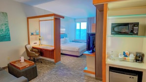 A hotel room with a bed, a desk with a chair, a microwave, and a mini-fridge. - SpringHill Suites by Marriott Macon (Macon)